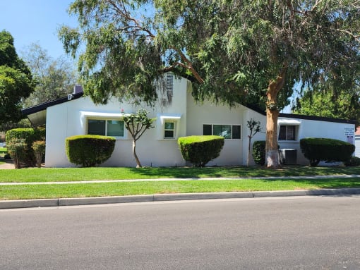 a white house with trees and bushes in front of it