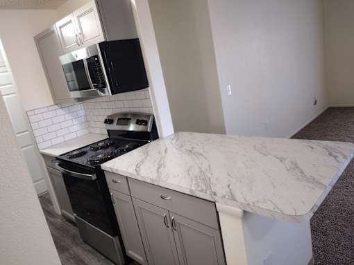 A kitchen with a marble countertop and stainless steel appliances.
