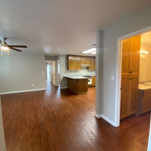 an empty living room with wood floors and a kitchen