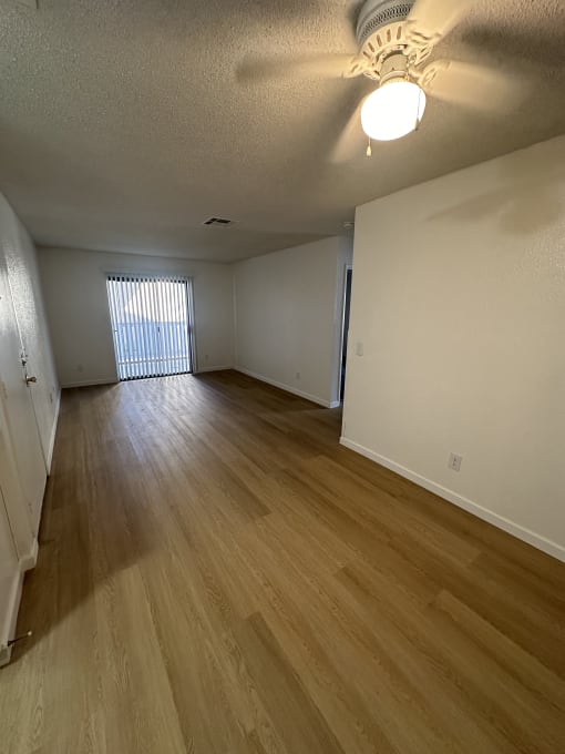 a view down a hallway with wood flooring and a window