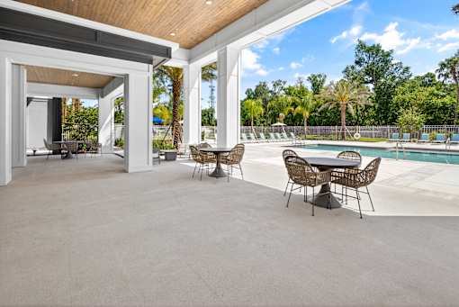 A patio with a table and chairs overlooking a pool.