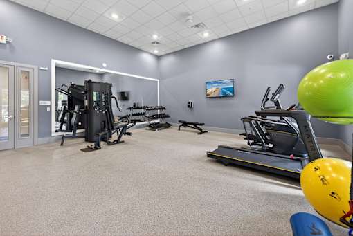 A gym with a variety of equipment including treadmills, weights, and exercise balls.