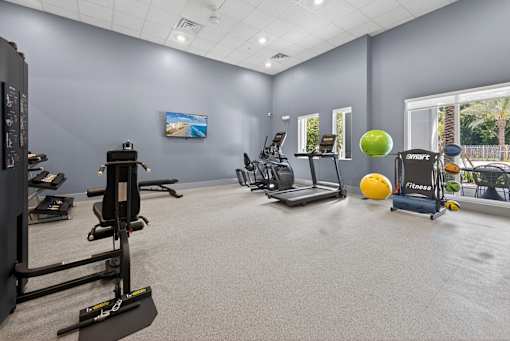 A gym with a variety of equipment including a treadmill, a stationary bike, and a rowing machine.