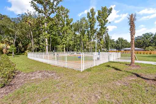 A white fence encloses a green field with trees.