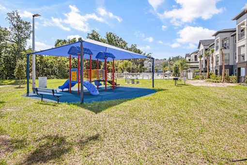 A playground with a blue canopy and red and yellow equipment.