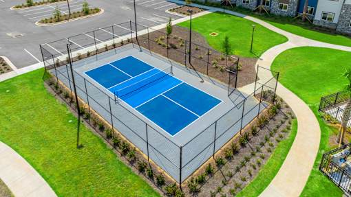 A tennis court surrounded by a fence and greenery.