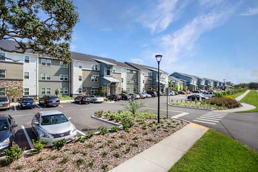 A parking lot with cars and apartment buildings in the background.