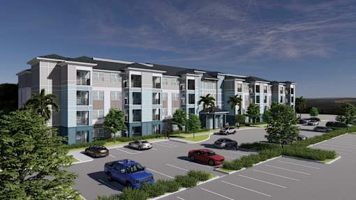 A blue car is parked in a parking lot in front of a building.