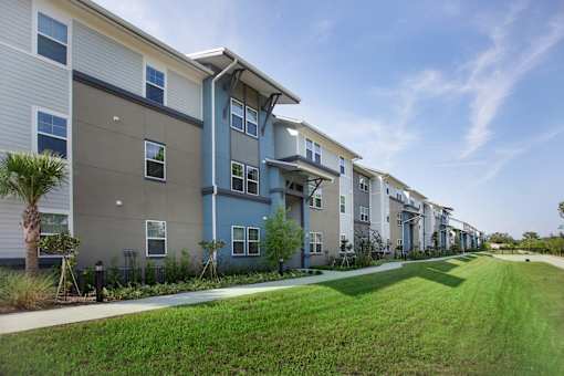 A row of modern townhouses with a green lawn in front.