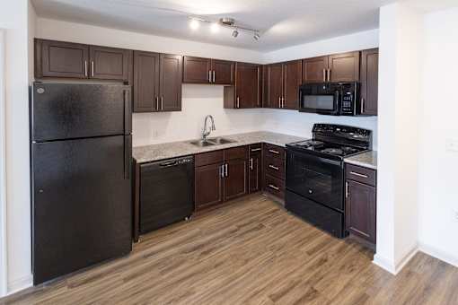 A kitchen with black appliances and brown cabinets.