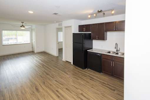 A kitchen with a black refrigerator and wooden floors.
