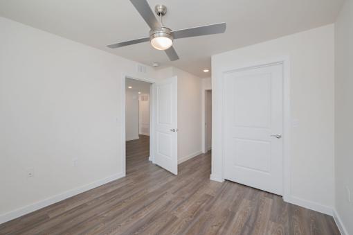A room with a ceiling fan and wooden flooring.