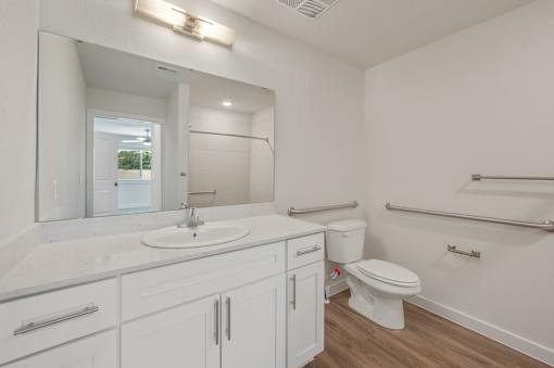 A white bathroom with a toilet, sink, and mirror.