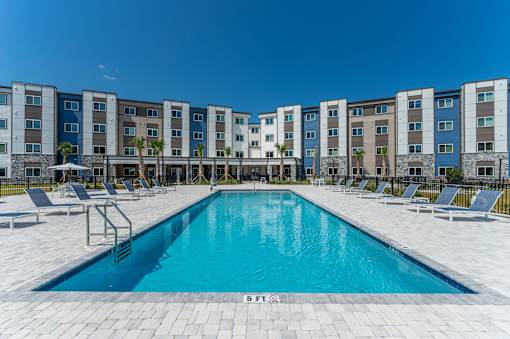 A swimming pool in front of a row of apartment buildings.