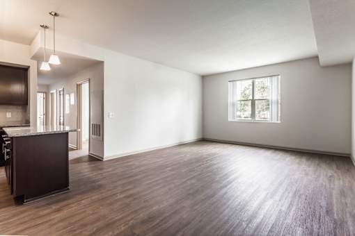 A large empty room with wooden floors and a window.