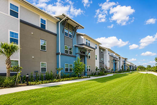 A row of modern apartment buildings with green lawns in front.