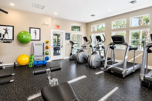 A gym with a variety of equipment including treadmills, exercise balls, and dumbbells.