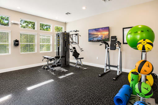 A home gym with a variety of equipment including a treadmill, weights, and a television.