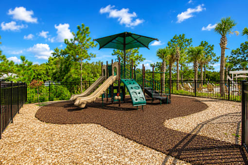 A playground with a green slide and a brown gravel area.