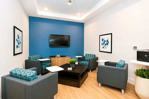 A living room with a blue wall and a flat screen TV.