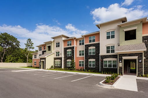 A row of modern townhouses with a parking lot in front.