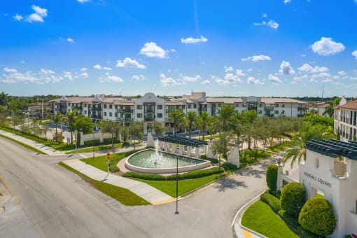 a fountain sits in the middle of a grassy area in front of a row of houses