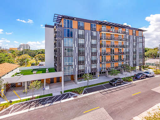 A modern multi-story building with orange and grey balconies.