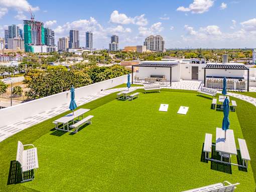 A park with a green lawn and picnic tables.