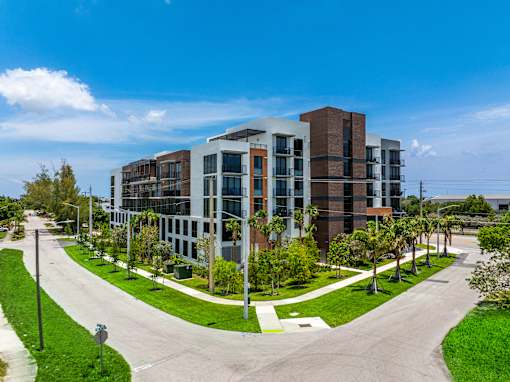 A modern multi-story building with a parking lot in front.