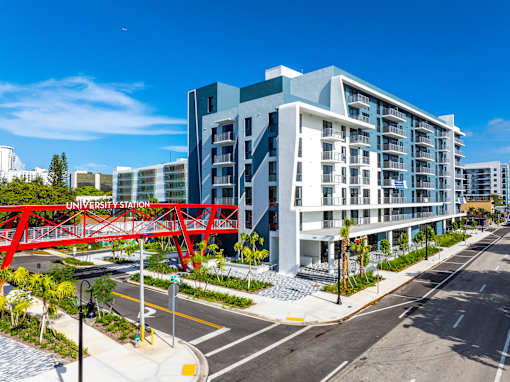 A modern building with a red bridge in front of it.