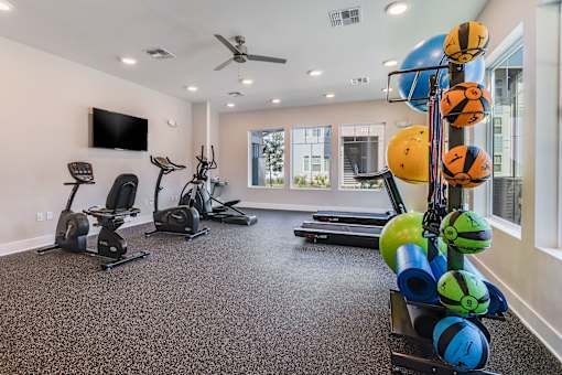 A spacious home gym with a variety of exercise equipment and a television.