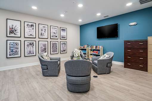 A living room with grey chairs and a television on the wall.
