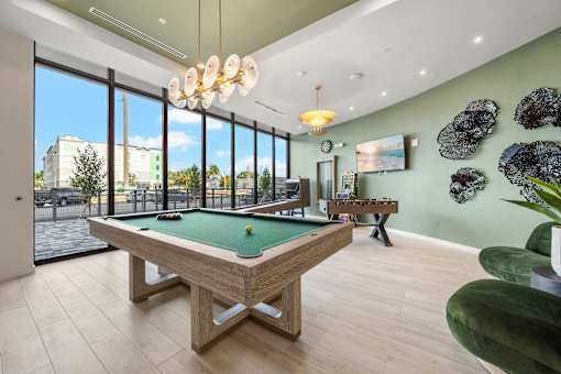 A pool table in a room with a green wall and a TV.