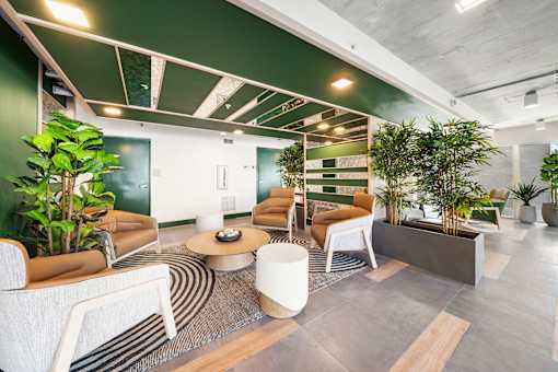 A modern office space with a green accent wall and a variety of seating options.