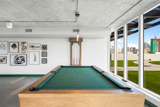 A pool table in a room with pictures on the wall.