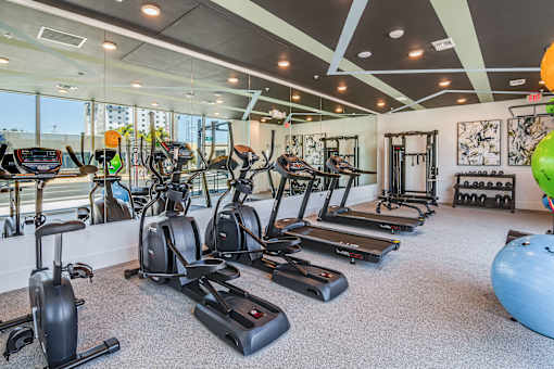 A gym with a variety of exercise equipment including treadmills, stationary bikes, and elliptical machines.