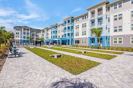 A sunny day at a modern apartment complex with a walkway and benches.