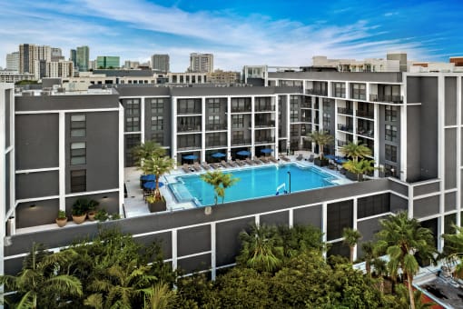 an aerial view of a large swimming pool with palm trees in front of a building