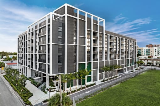 a rendering of a white and gray apartment building with trees in front of it