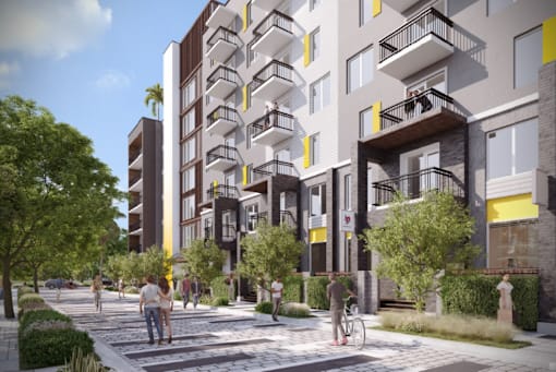 A modern apartment complex with balconies and a pedestrian walkway in front.
