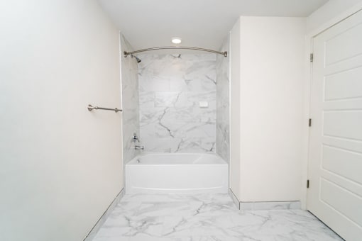A white bathroom with a marble tub and shower.