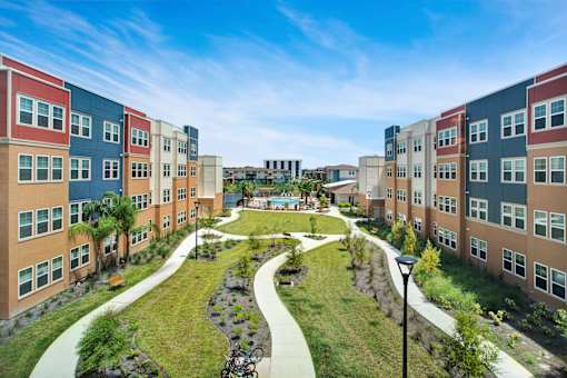 A view of a courtyard surrounded by buildings with a bicycle parked on the grass.