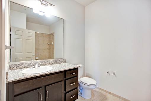 A bathroom with a sink, toilet and mirror.