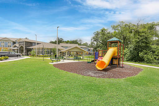 A playground with a yellow slide and a green roofed structure.