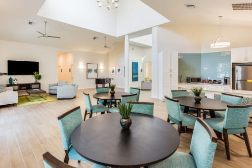a communal area with tables and chairs and a kitchen in the background