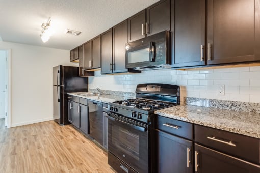 a kitchen with dark cabinets and granite countertops