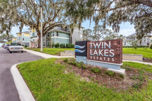 a sign that says twin lakes estates with houses in the background