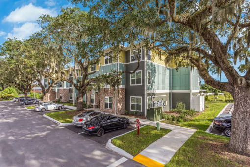 an apartment building with a parking lot and trees in front of it
