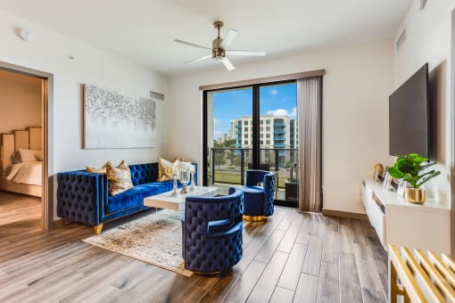 a living room with hardwood flooring and a sliding glass door leading to a balcony