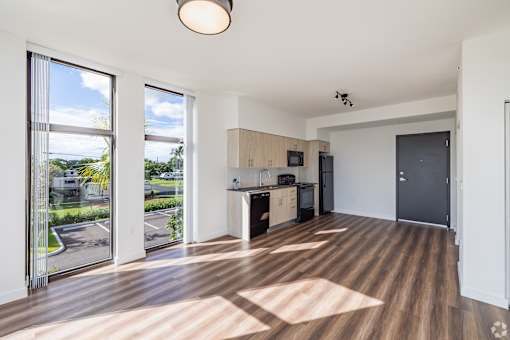 A spacious kitchen and living room with wooden flooring and large windows.